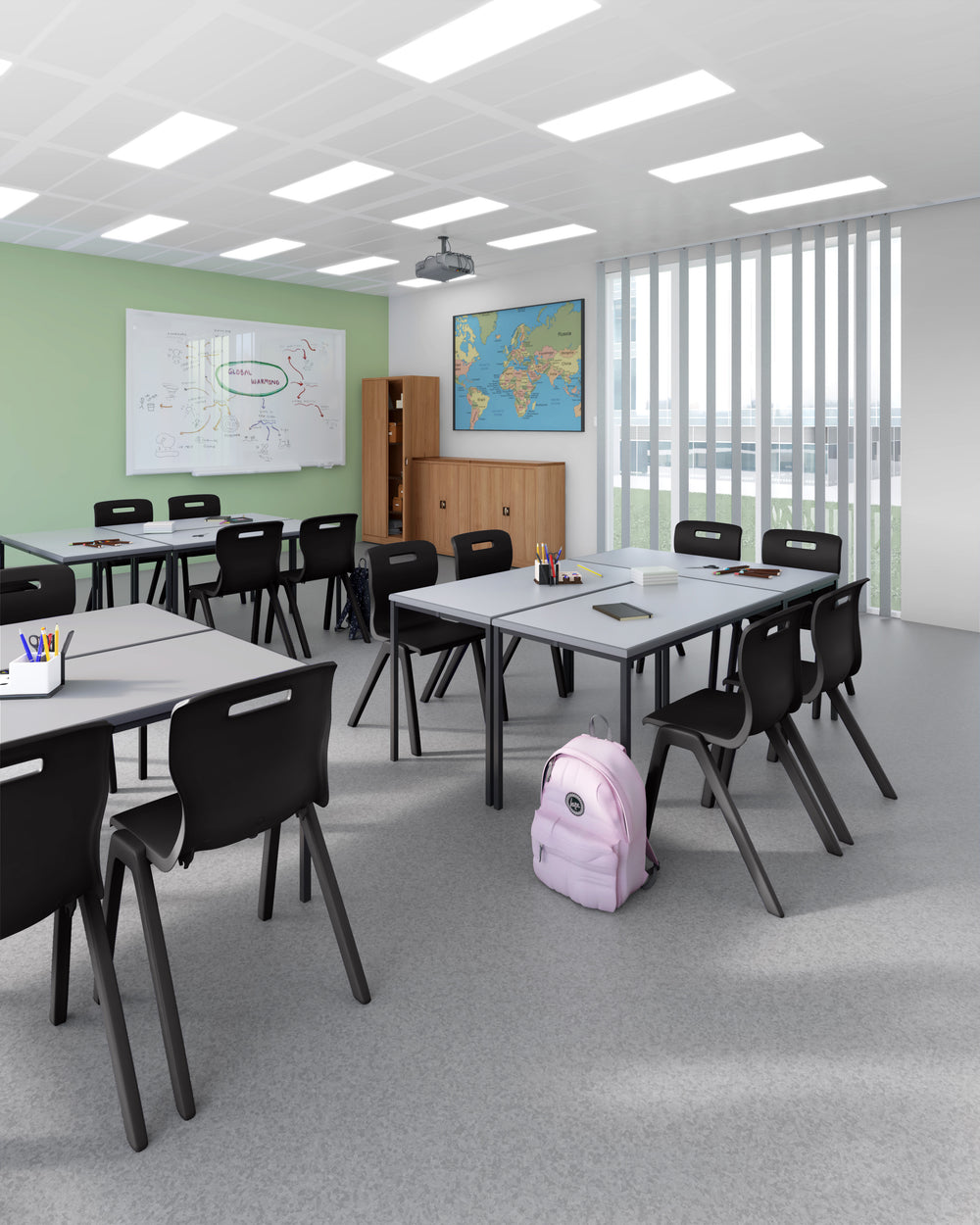 A modern classroom interior with multiple rectangular desks, black chairs, a green wall, a world map on the wall, a projector, and a light pink backpack on the floor.